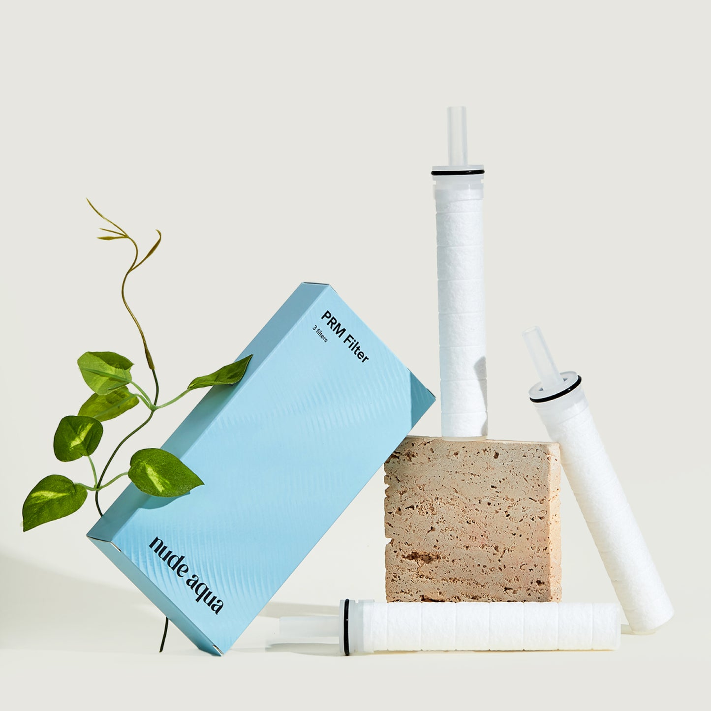 Nude Aqua water filter components including a filter cartridge, sponge, and packaging on a light background.