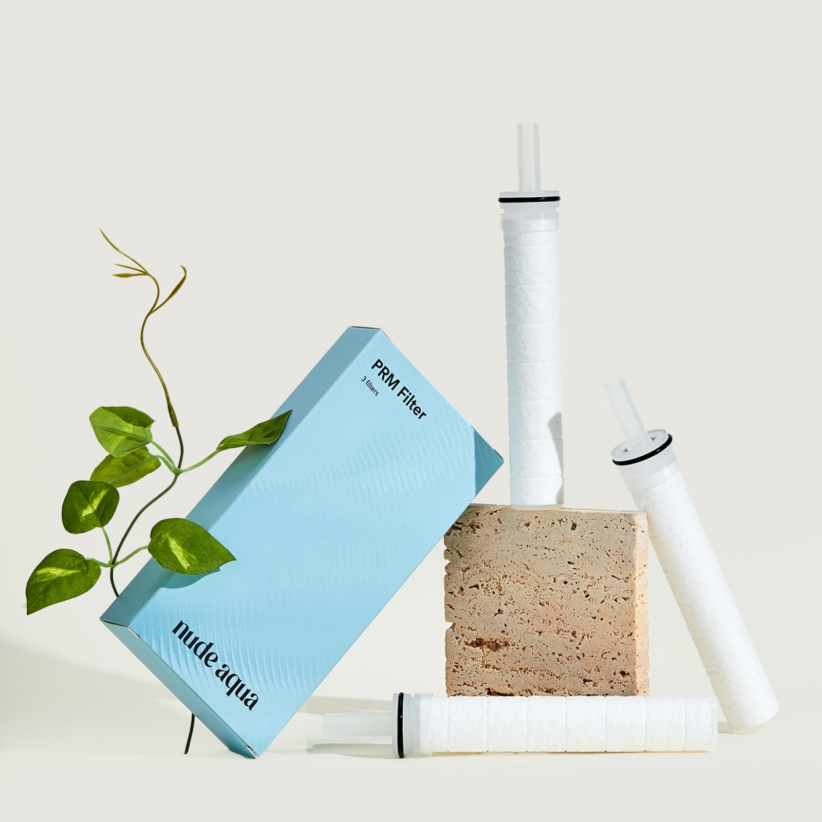 Nude Aqua water filter components including a filter cartridge, sponge, and packaging on a light background.